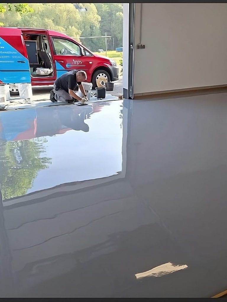 Ein Mitarbeiter tägt Epoxidharz auf einen Boden auf.